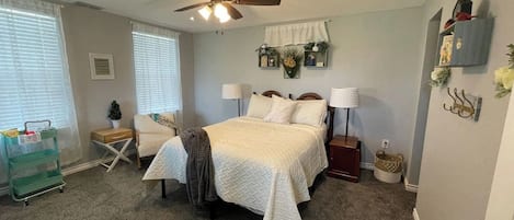 A bedroom with a bed, ceiling fan, bedside lamps, and a nightstand.