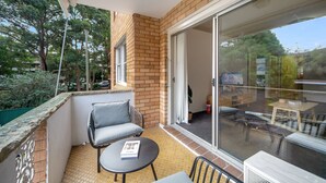 A balcony with a table and chairs, a sliding glass door, and a view of the outdoors. - Cosy & Convenient Place in Inner West Area (no parking) (Strathfield)