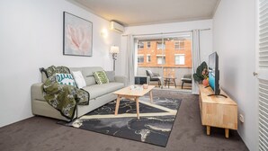 A modern living room with a sofa, coffee table, and a flat-screen TV. - Cosy & Convenient Place in Inner West Area (no parking) (Strathfield)