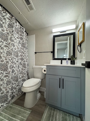 A bathroom with a toilet, a sink with a mirror, and a shower curtain with a floral pattern.