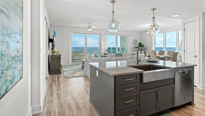 A modern kitchen with a large island, dark cabinetry, and pendant lighting.
