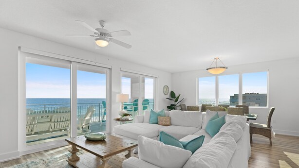 A spacious living room with a white sofa, a wooden coffee table, and a view of the ocean.