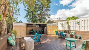 A wooden deck with outdoor seating, including chairs and tables, surrounded by a bamboo fence and trees. - The Mermaid at Tiny House Siesta (Sarasota)