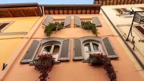 Eine Gebäudefassade mit Bogenfenstern, Fensterläden und Blumenkörben.