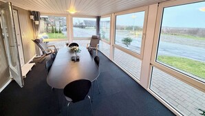 Un salón de conferencias con una larga mesa, sillas y ventanas amplias que ofrecen vistas al exterior.
