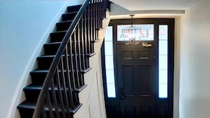 A staircase leading to a dark wooden door with a window above it. - Modern Suite on the River (Port Hope)