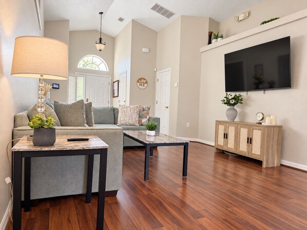 A modern living room with a sofa, coffee table, TV, and a lamp.