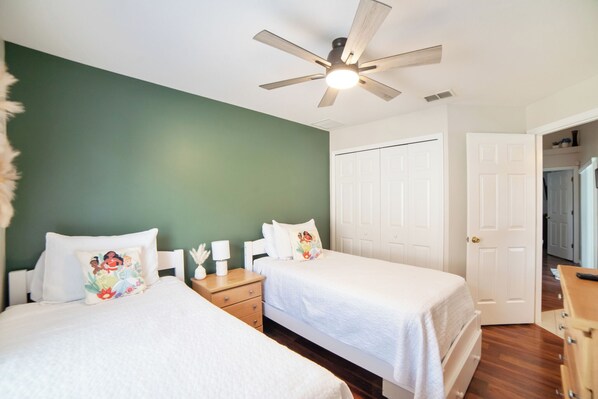 A bedroom with two beds, a ceiling fan, and white doors.