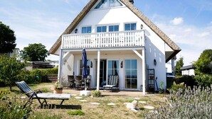 A white house with a balcony, a covered patio, and a lawn with outdoor furniture. - Close to the sea, quiet location, use of swimming pool and sauna - Reethaus Göhren FeWo 01 (Göhren)