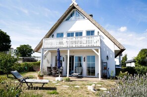 A white house with a balcony, a covered patio, and a lawn with outdoor furniture. - Close to the sea, quiet location, use of swimming pool and sauna - Reethaus Göhren FeWo 01 (Göhren)