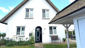 A white building with a steeply pitched roof and a black door. There are two windows on the upper floor and one on the ground floor. - Close to the sea, quiet location, use of swimming pool and sauna - Reethaus Göhren FeWo 01 (Göhren)