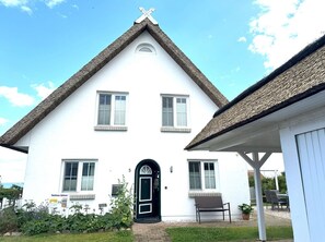 A white building with a steeply pitched roof and a black door. There are two windows on the upper floor and one on the ground floor. - Close to the sea, quiet location, use of swimming pool and sauna - Reethaus Göhren FeWo 01 (Göhren)