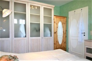 Une chambre à coucher avec un lit, une armoire aux portes en verre dépoli, une porte en bois et une serviette blanche accrochée au mur.