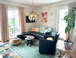 Uma sala de estar moderna com sofá modular, uma poltrona preta, mesa de centro redonda e luminária pendente.
