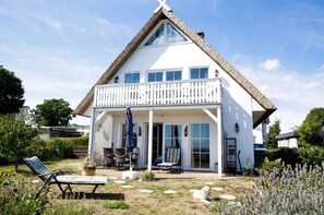 A white house with a balcony, a covered patio, and a lawn with outdoor furniture. - Close to the sea, quiet location, use of swimming pool and sauna - Reethaus Göhren FeWo 01 (Göhren)