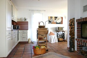 A compact kitchen with white cabinets, a microwave, and a brick fireplace. - Close to the sea, quiet location, pool and sauna - Reethaus Göhren FeWo 01 (Göhren)