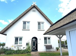 A white building with a steeply pitched roof and a black door. There are two windows on the upper floor and one on the ground floor. - Close to the sea, quiet location - Reethaus Göhren FeWo 02 - Reethaus Göhren (Göhren)