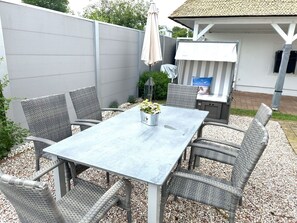 A patio with a table and chairs, a grill, and a covered seating area. - Close to the sea, quiet location - Reethaus Göhren FeWo 02 - Reethaus Göhren (Göhren)