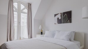 Ein Schlafzimmer mit einem Bett, einem Nachttisch, einer Lampe und zwei Wandbildern.