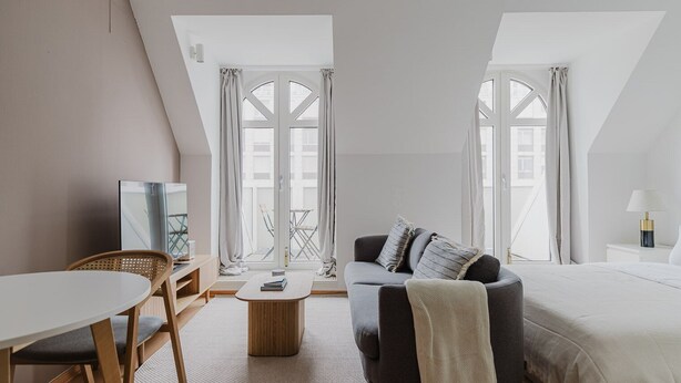 Ein modernes Hotelzimmer mit einer Couch, einem Bett, einem kleinen Tisch und einem Fernseher.