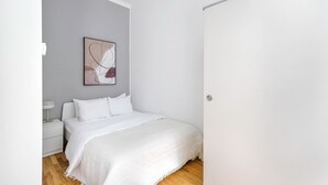 A minimalist bedroom with a bed, a nightstand, a wall-mounted abstract artwork, and a white door. - Chic Döbling 1BR, Move-In-Ready w/ Furniture, by Blueground (Vienna)