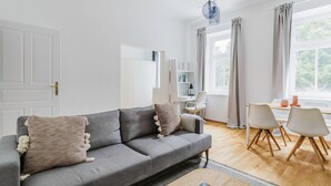 A modern living room with a grey sofa, a wooden coffee table, and a dining area with white chairs. - Chic Döbling 1BR, Move-In-Ready w/ Furniture, by Blueground (Vienna)