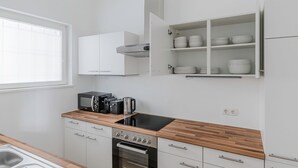 A modern kitchen with white cabinetry, a wooden countertop, a built-in oven, a microwave, and a coffee maker. - Chic Döbling 1BR, Move-In-Ready w/ Furniture, by Blueground (Vienna)