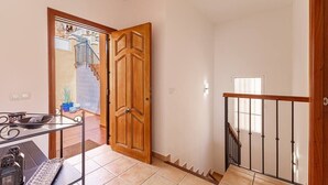 A hallway with a wooden door, a staircase, and a small table with a keyboard and mouse. - Private villa in Tamango Hill (Torrox)