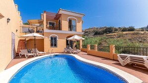 A two-story building with a swimming pool, sun loungers, and umbrellas. - Private villa in Tamango Hill (Torrox)