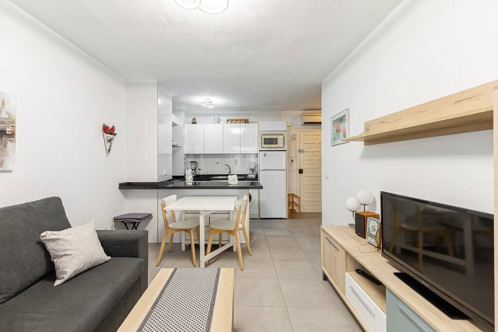 Un espacio habitable compacto con kitchenette, comedor, sofá y televisor.