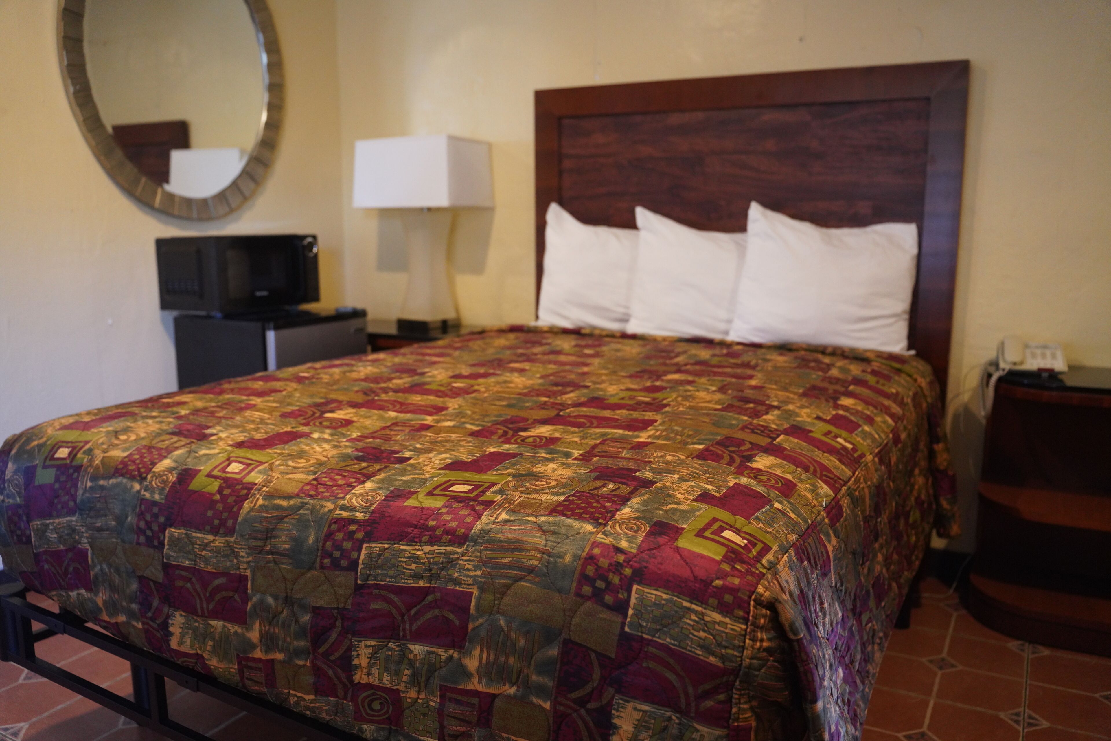 A hotel room with a bed, a television, a lamp, and a nightstand.