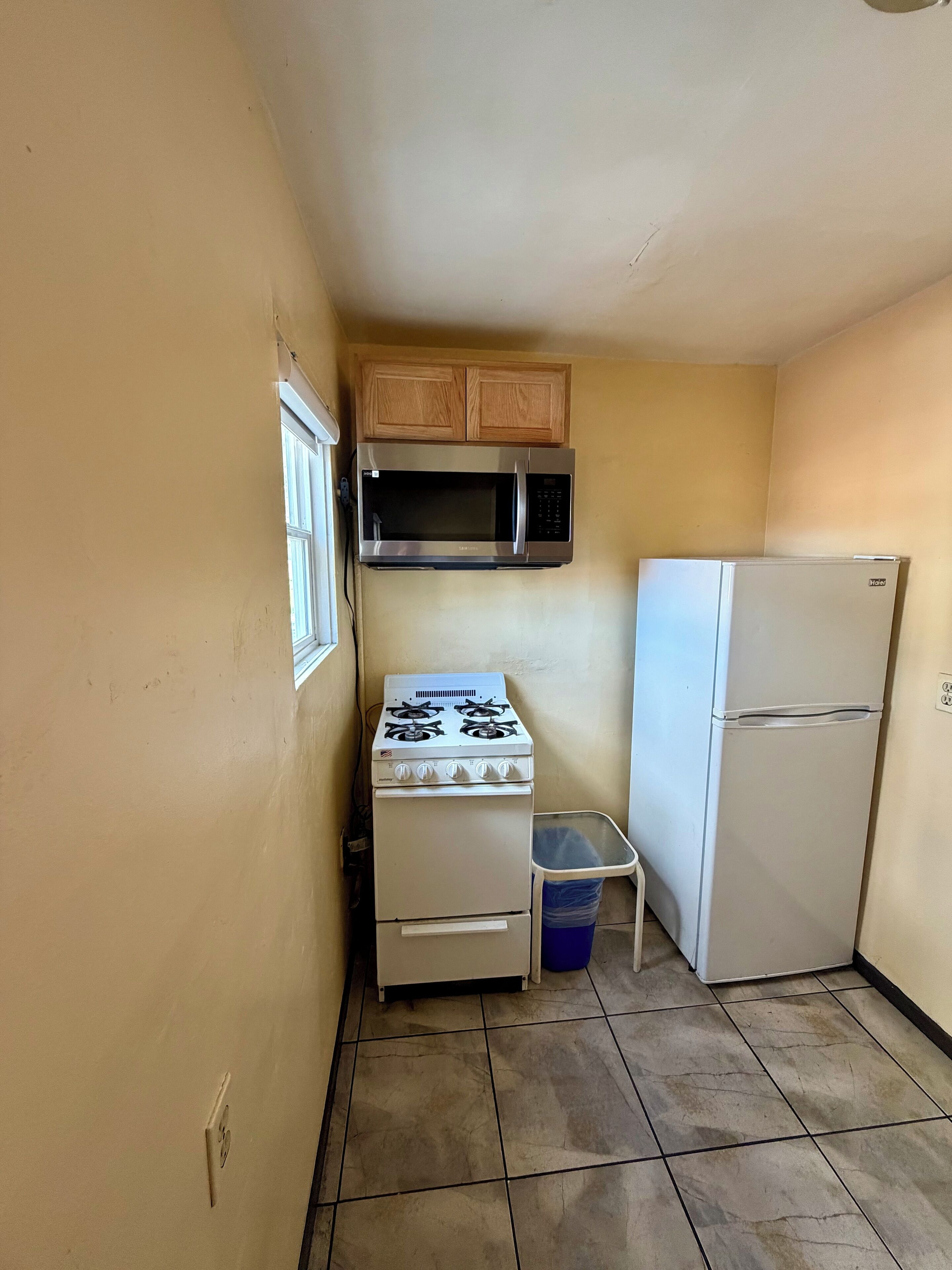 Una cocina pequeña con estufa, microondas y refrigerador.