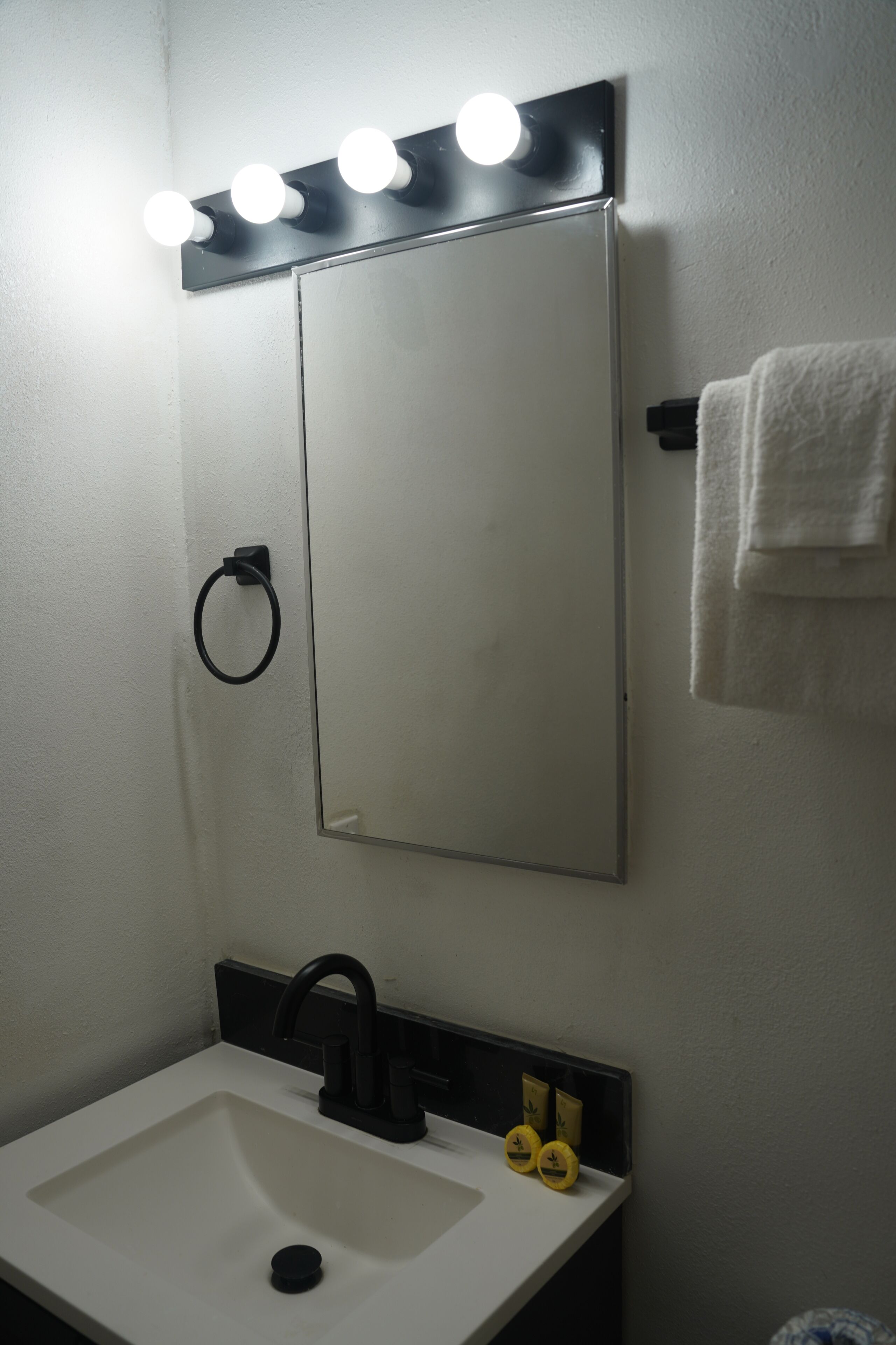 A bathroom with a mirror, sink, and towel rack.