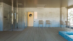 Un espace spa moderne doté d’une terrasse en bois, d’une douche en verre et d’une petite piscine.