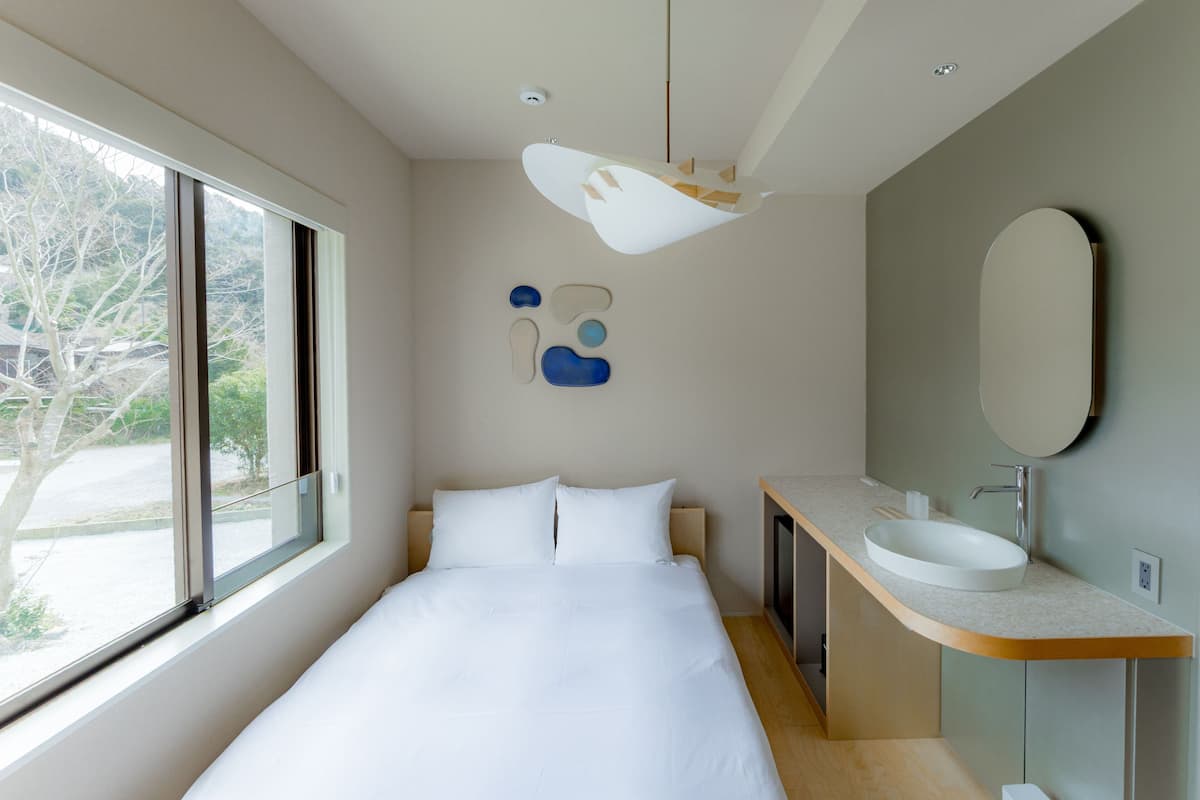 A modern bedroom with a large bed, a built-in vanity, and a large window.