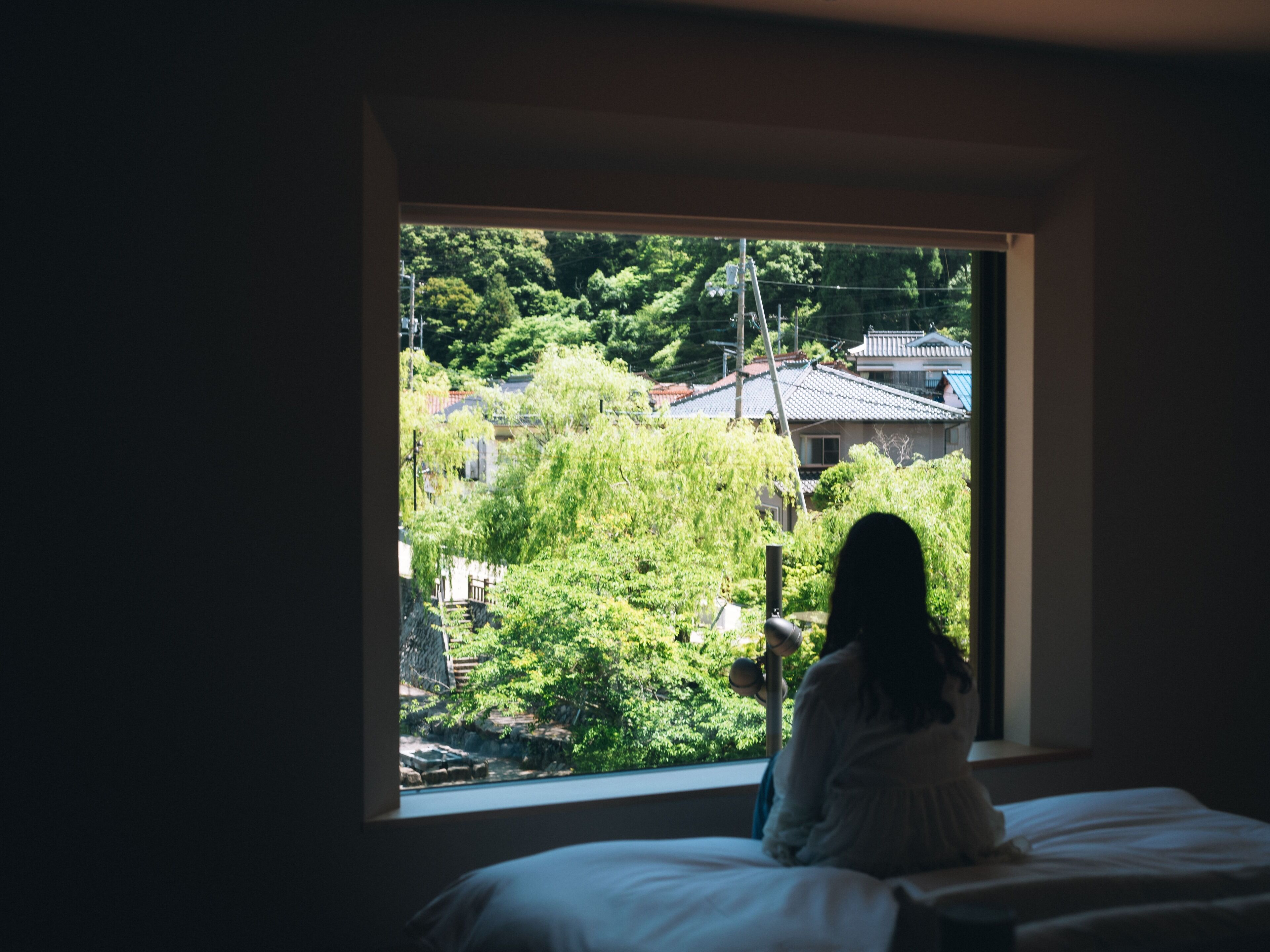 A room with a large window overlooking a residential area with houses and greenery.