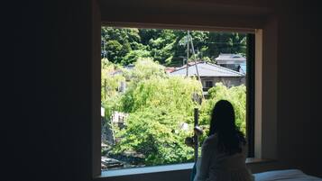 A room with a large window overlooking a residential area with houses and greenery.