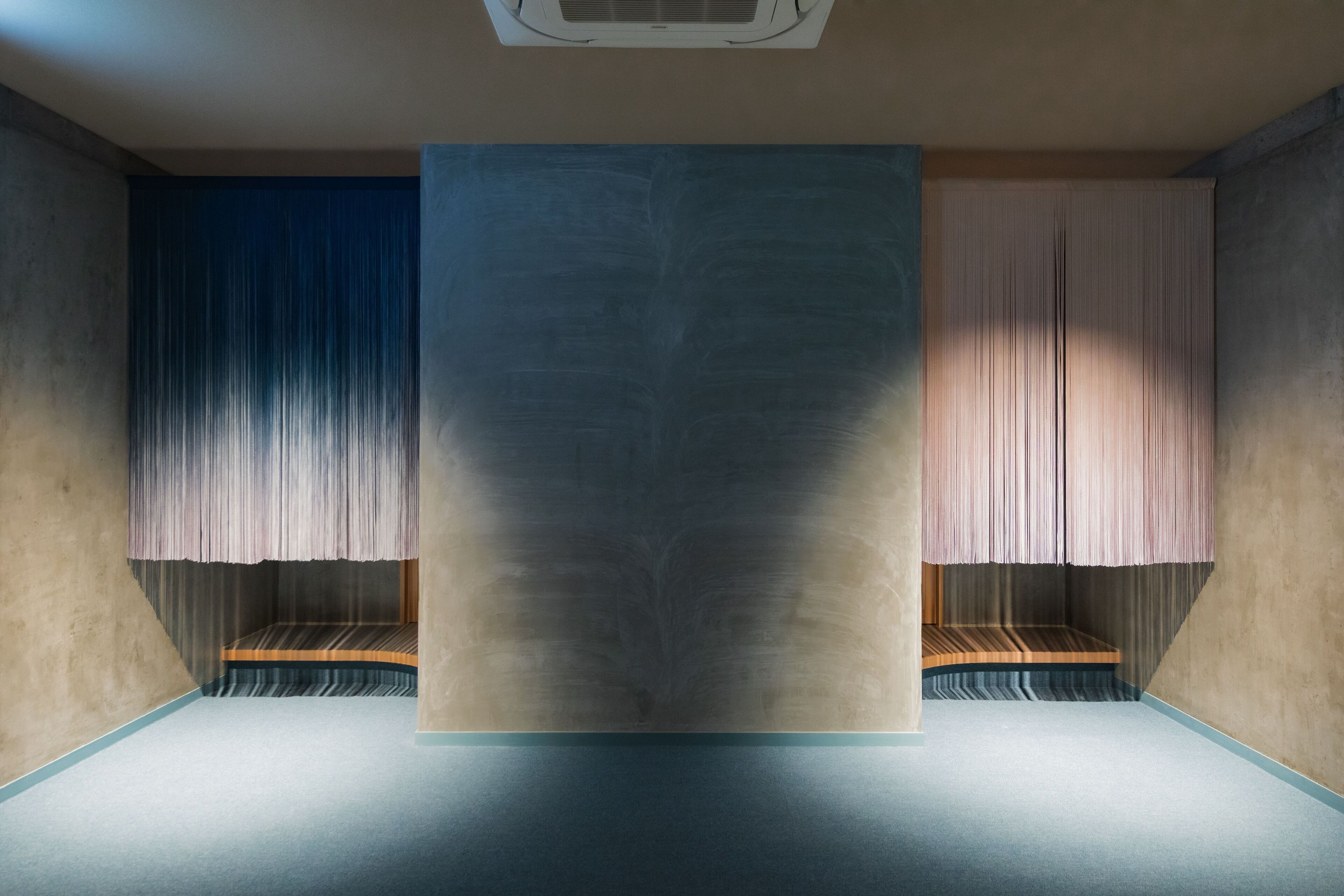 A room with a large central window, a ceiling vent, and a wooden bench against the wall.