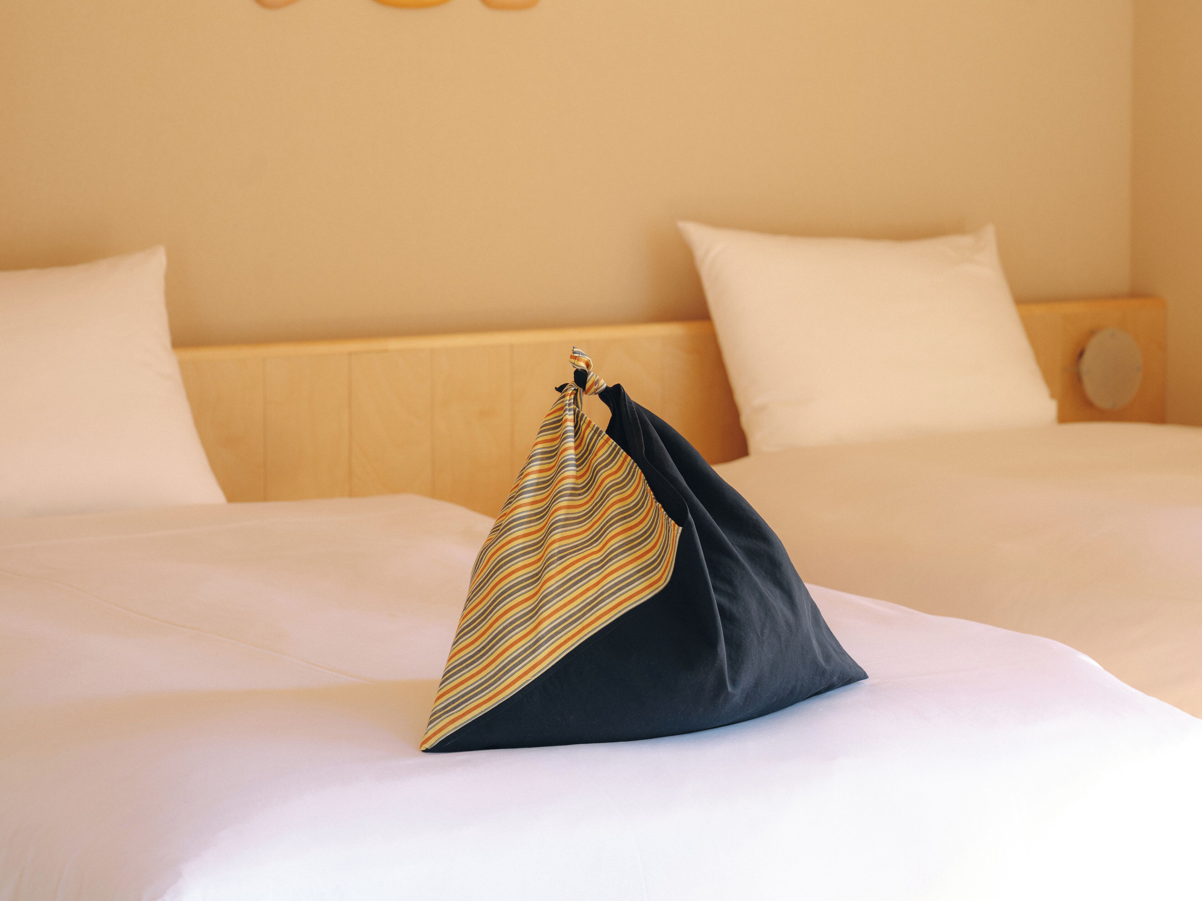 A neatly made bed with white linens and a striped pillow.
