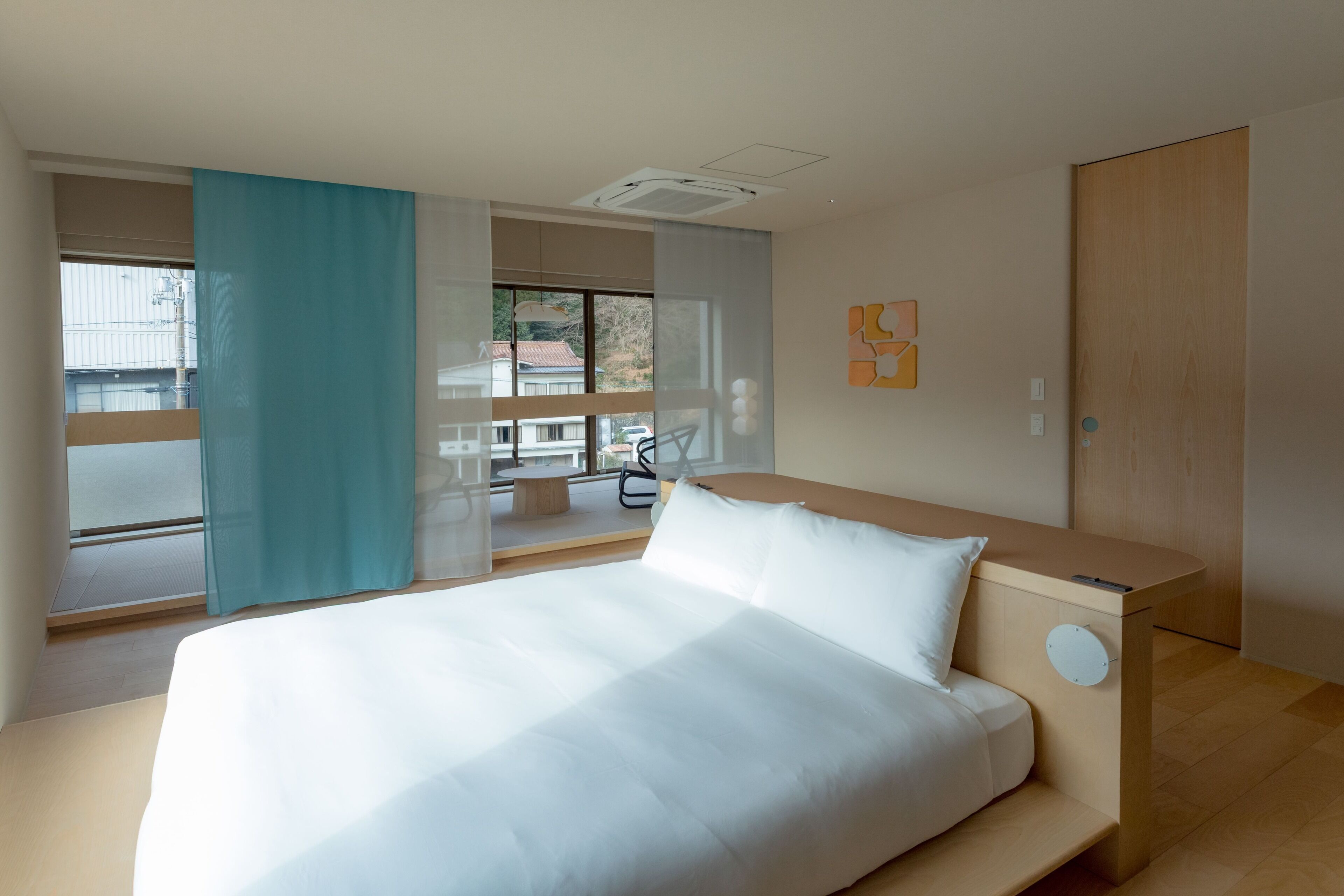A modern hotel room with a large bed, a wooden desk, and a view of the outside.