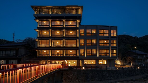 Un hôtel à plusieurs étages, doté d’une architecture alliant tradition et modernité, avec une base en pierre et une partie supérieure en bois.
