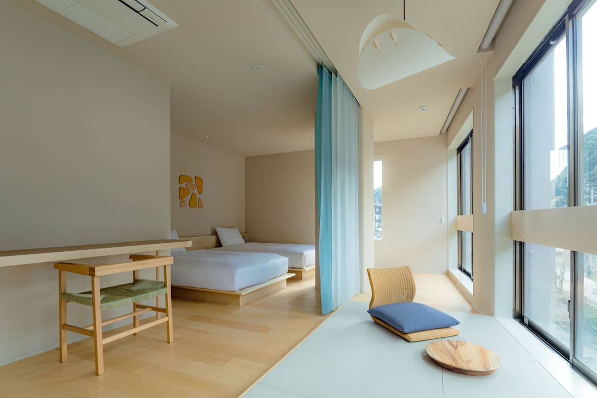 A modern hotel room with a large bed, a small desk, and a view of the outdoors.