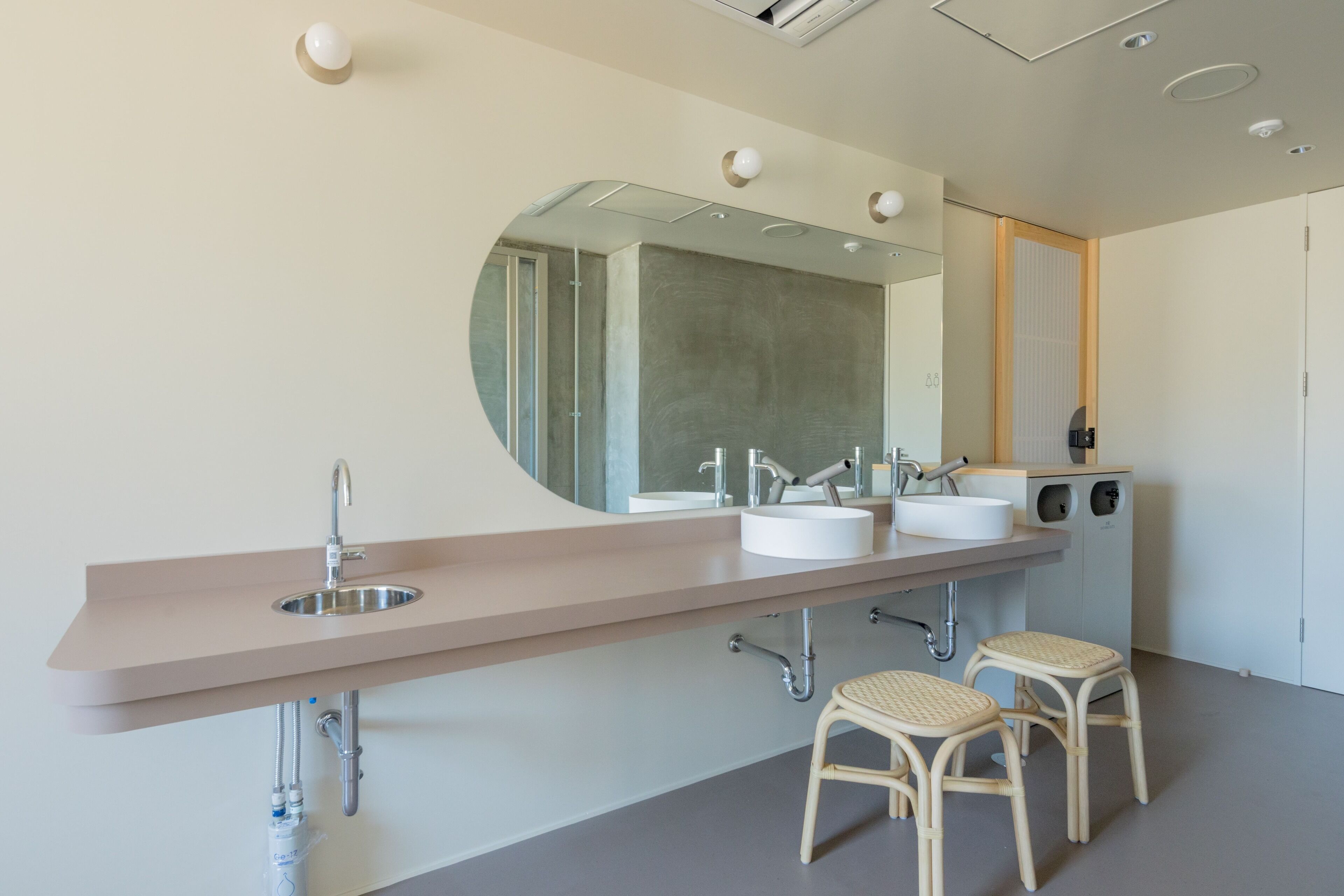 A modern bathroom with a long vanity, two sinks, a large mirror, and a toilet.