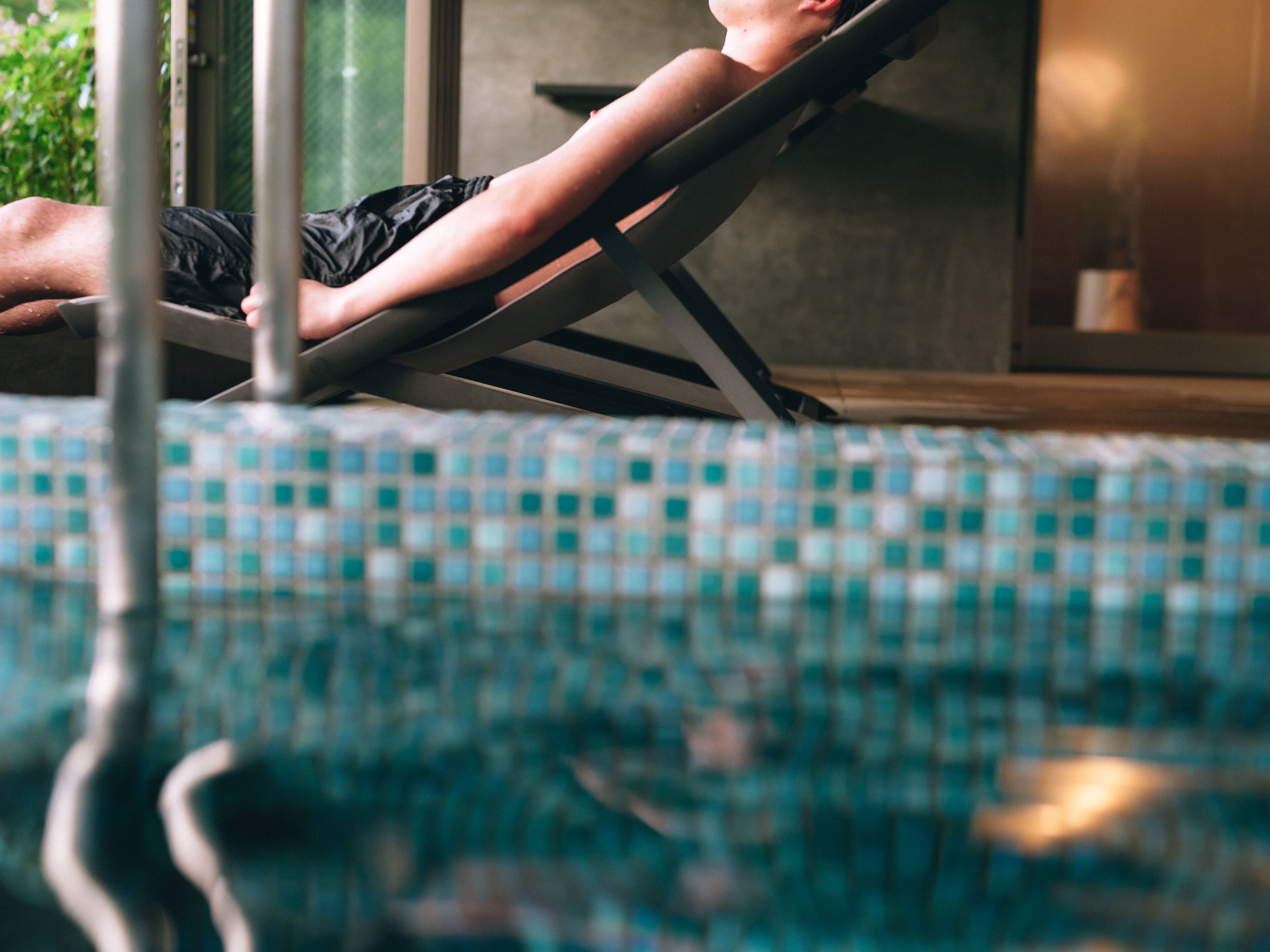 Una persona sdraiata su un lettino da piscina con pavimento piastrellato.
