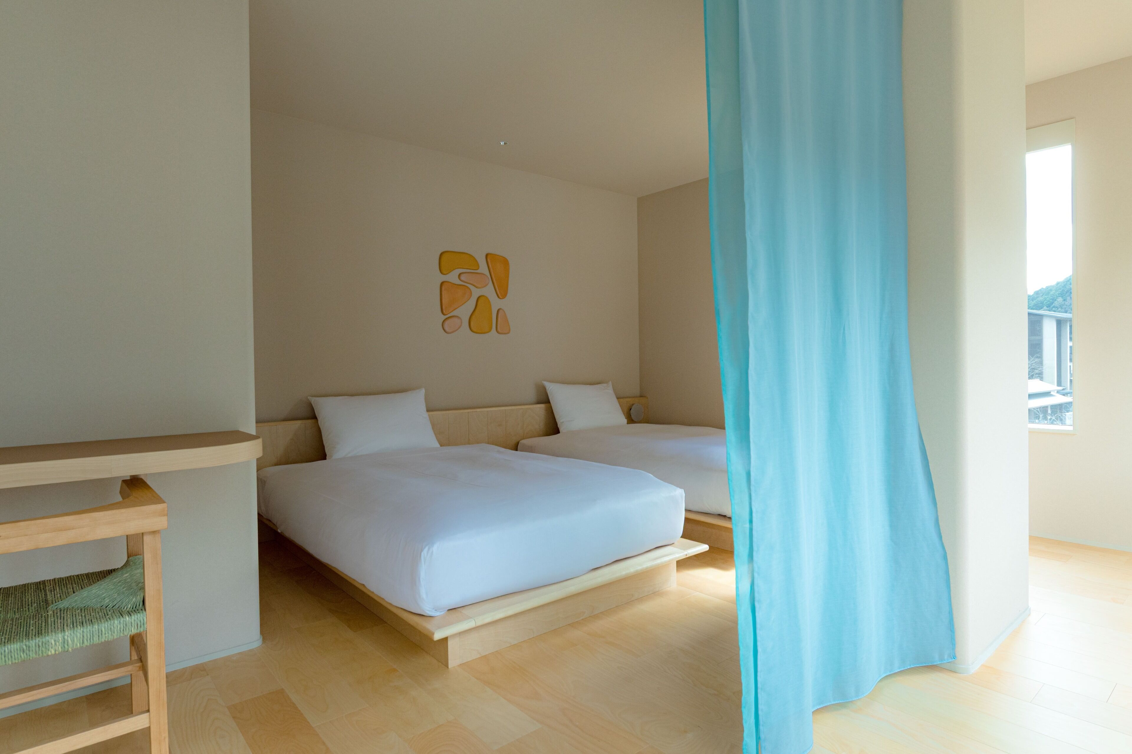 Un dormitorio moderno con dos camas, un banco de madera y una obra de arte en la pared.