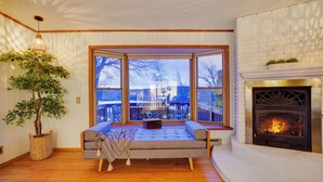 A cozy living room with a large window, a fireplace, and a comfortable seating area. - Arrowhead Premier Lakefront w/Sauna, Hot Tub, Firepit, Game Room, Amenities, (Pocono Lake)