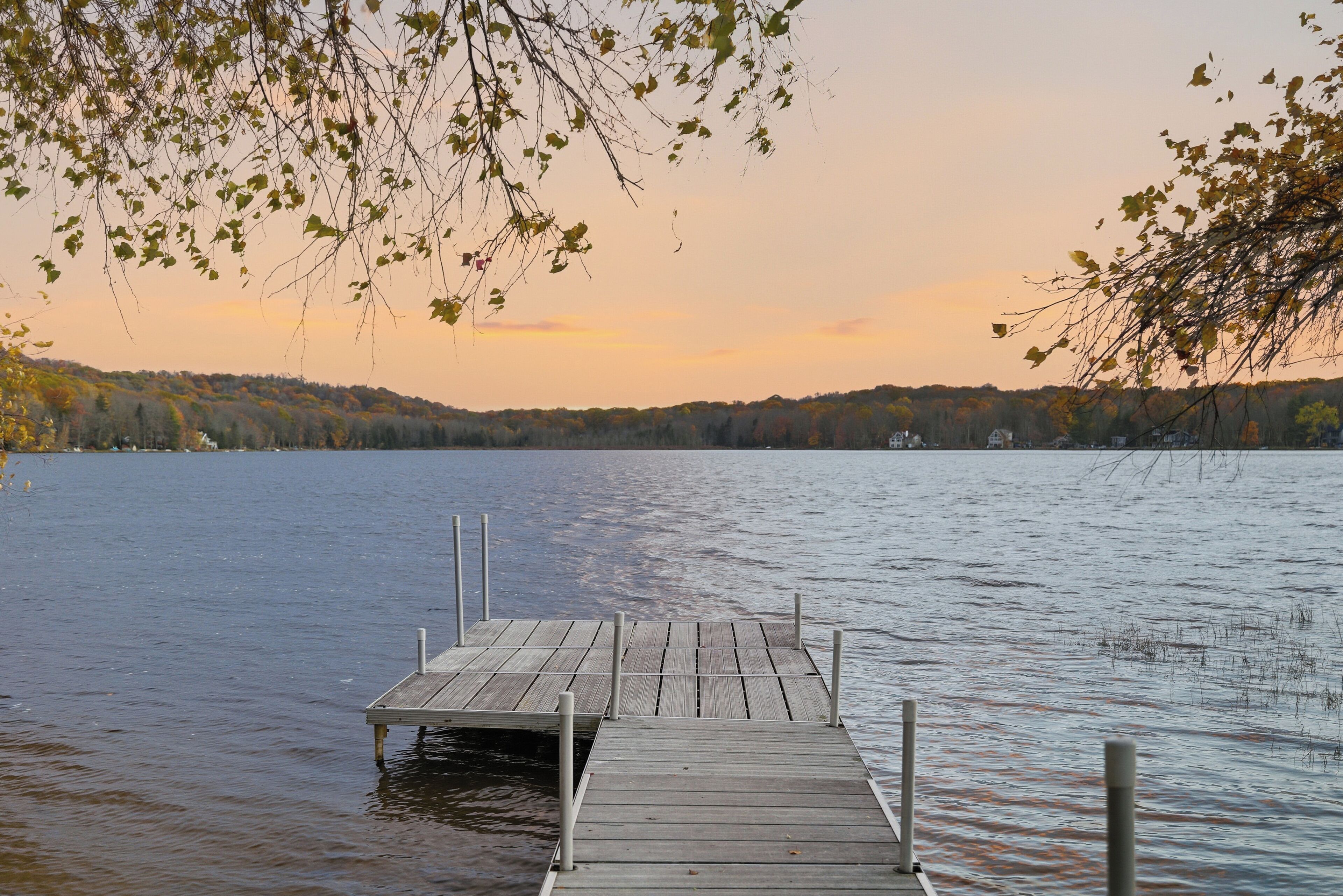 A wooden dock extending into a calm lake with a forested shoreline in the background.