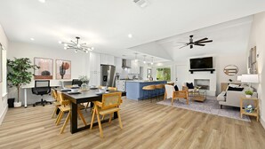 A spacious kitchen with modern appliances, a dining area with wooden chairs, and a living room with a sofa and TV. - Designer Home,  Sleep 8,  Ask us about FREE add-ons (Austin)