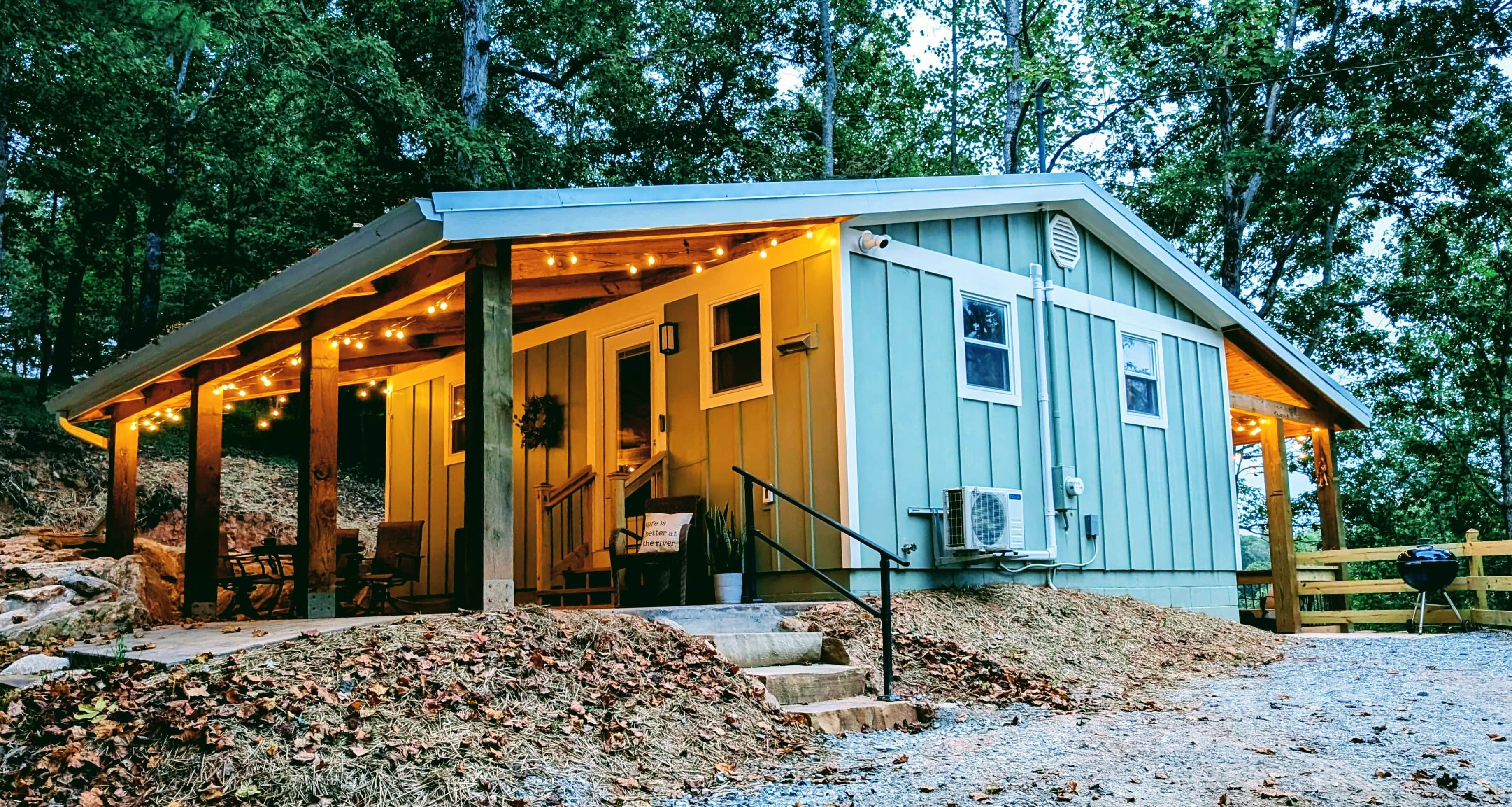 A rustic cabin with a porch, wooden deck, and a covered seating area.