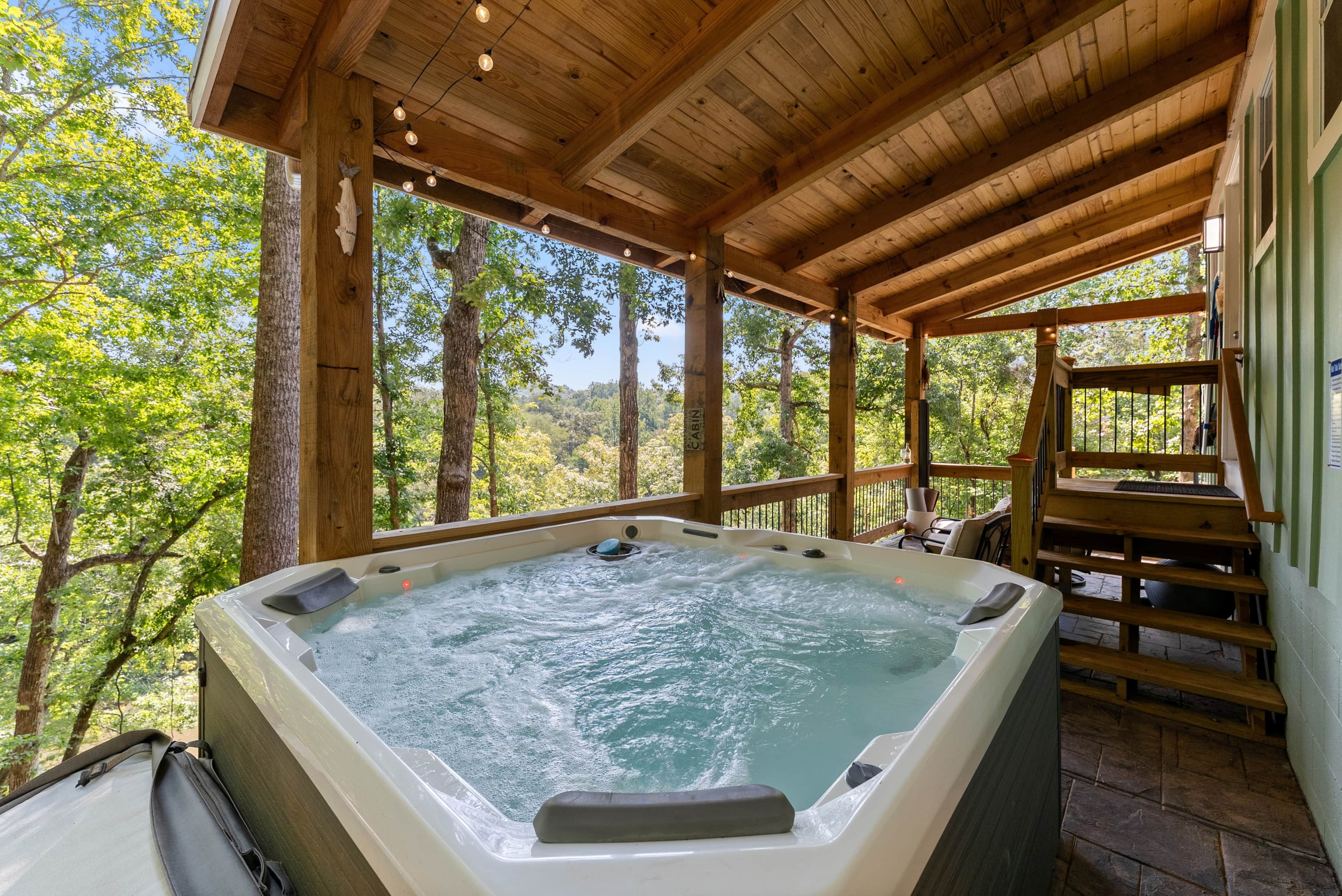 Un jacuzzi bajo un pabellón de madera con vista a un bosque.